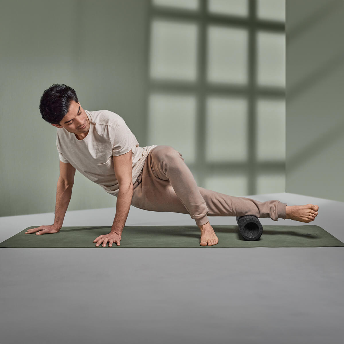 Ein Mann rollt sein Bein in Seitenlage mit abgestützten Armen über die Maxi-Faszienrolle von Liebscher & Bracht.